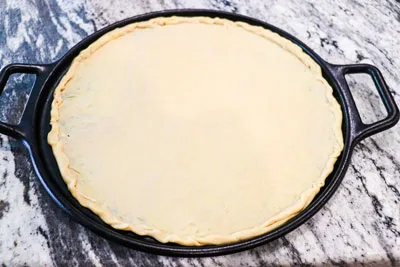 Chickpea dough rolled out thin into 14 inch round pizza