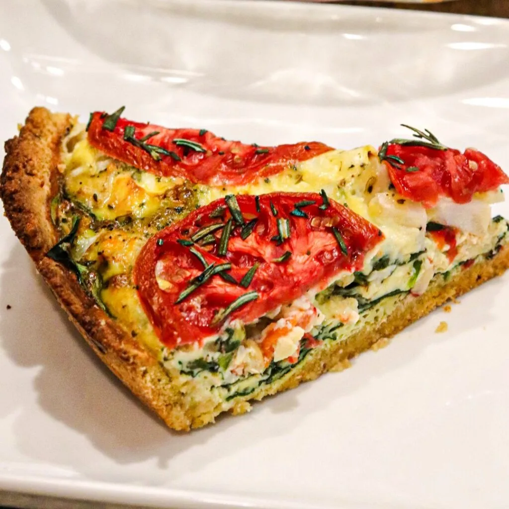 Slice of Tuscan Quiche with Garbanzo Bean Crust served in the white plate