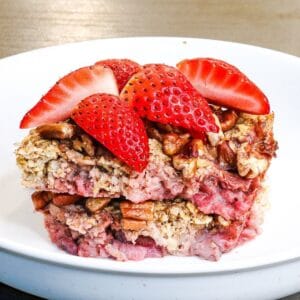 Baked oats topped with fresh strawberries served on a white plate